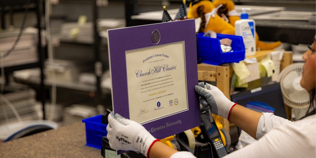 hands holding up a custom frame mat in a US-manufacturing facility