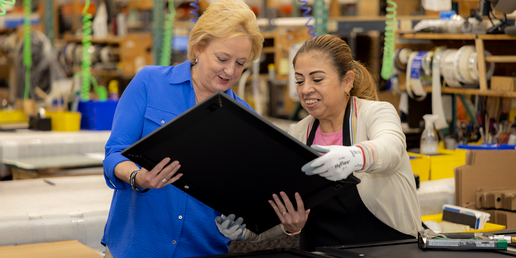 Lucie Voves and an employee holding and looking at a custom frame
