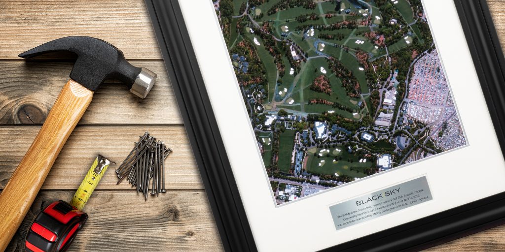 hammer, measuring tape, and nails next to custom photo frame with engraved plate on wood table