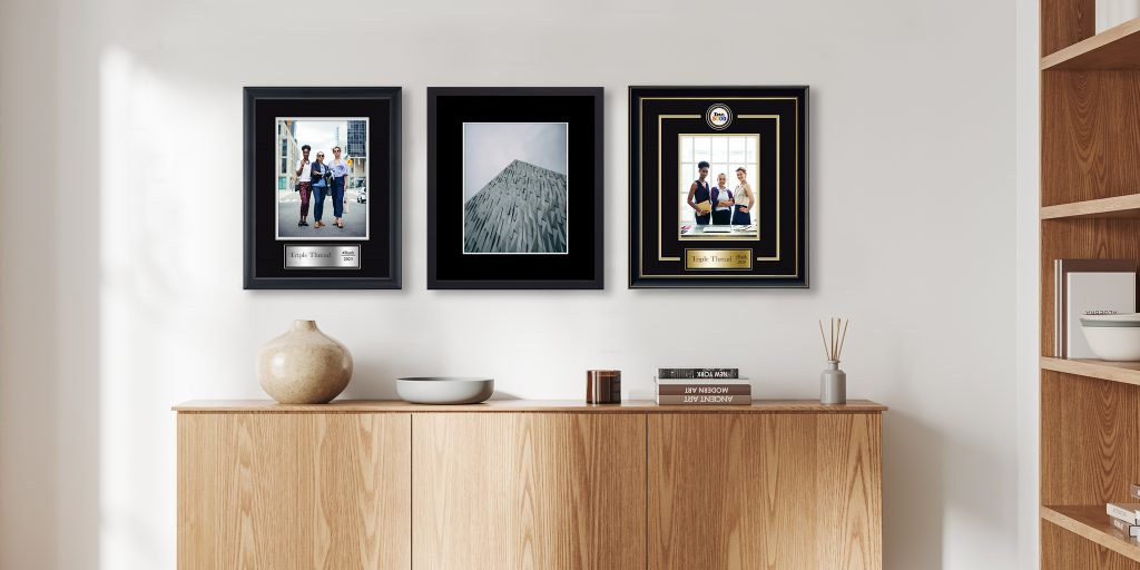 three custom frames and awards in a linear layout hung on wall in an office space