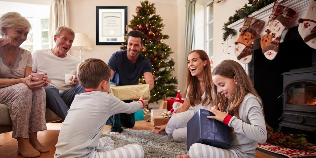 family smiling and passing around christmas gifts with custom frame on wall in background