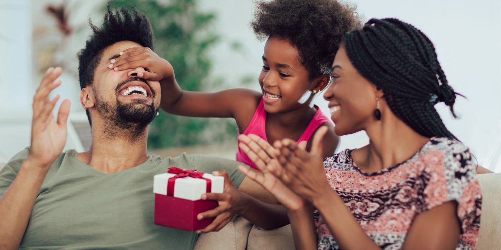 mother and daughter handing dad a custom father's day gift